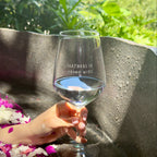 Hand holding the Partners in Wine glass outdoors in a stone bath.