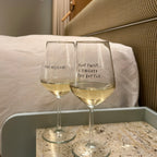 Two wine glasses filled with white wine on a hotel room bedside table. 