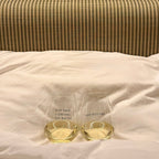 Two wine glasses - Pour Decisions and Plot Twist filled with white wine on a striped bed