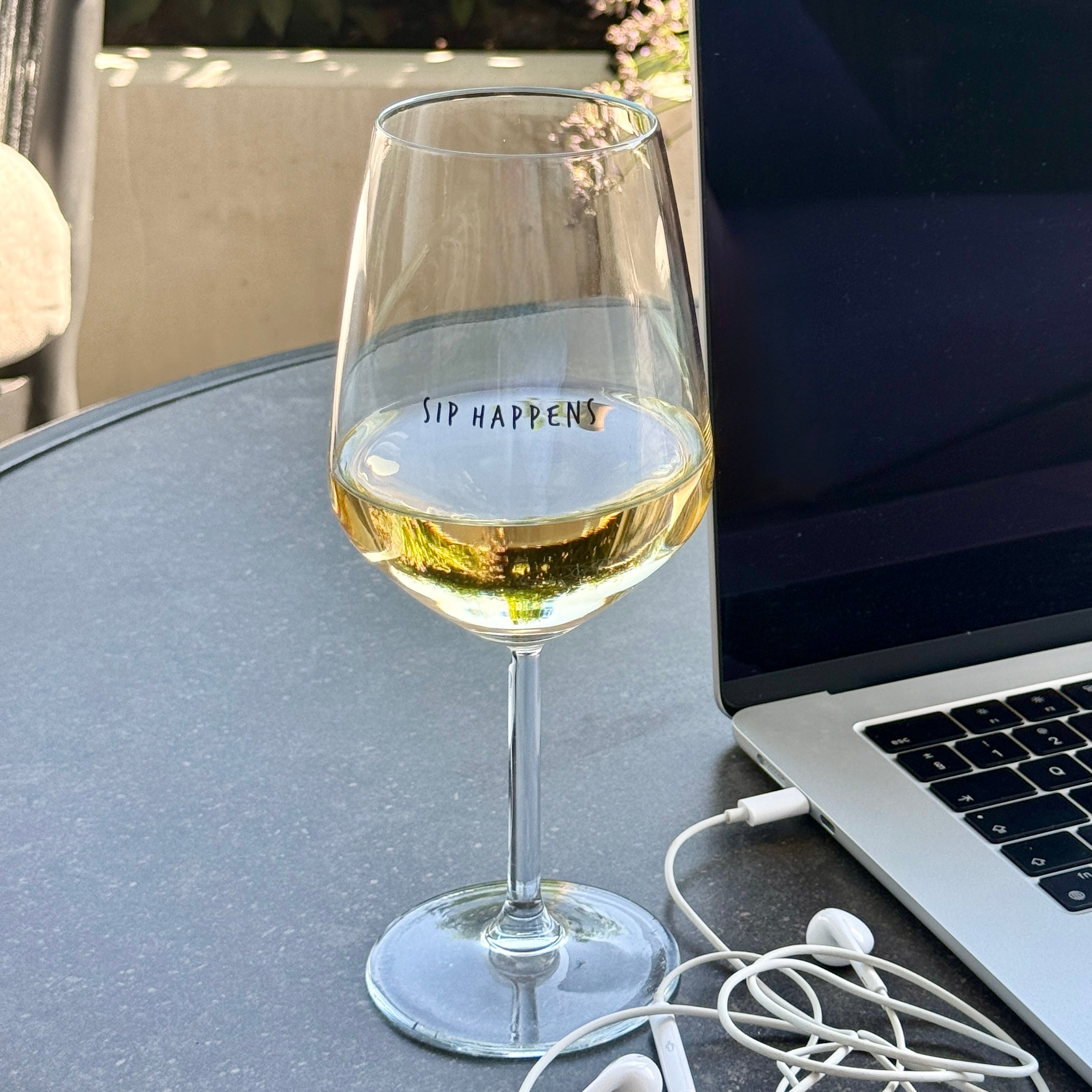 Sip Happens wine glass filled with white wine on a marble table, front angle